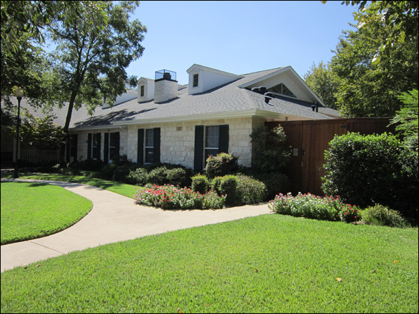 a house with a driveway and trees in the background