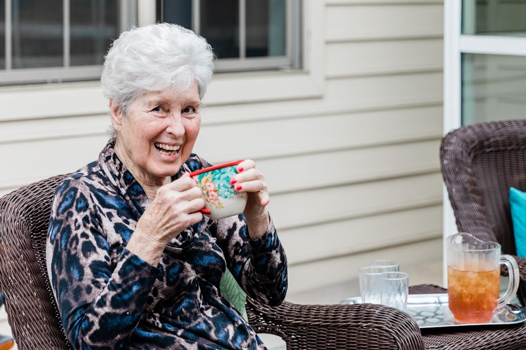 an older woman sitting on a patio chair and eating a snack