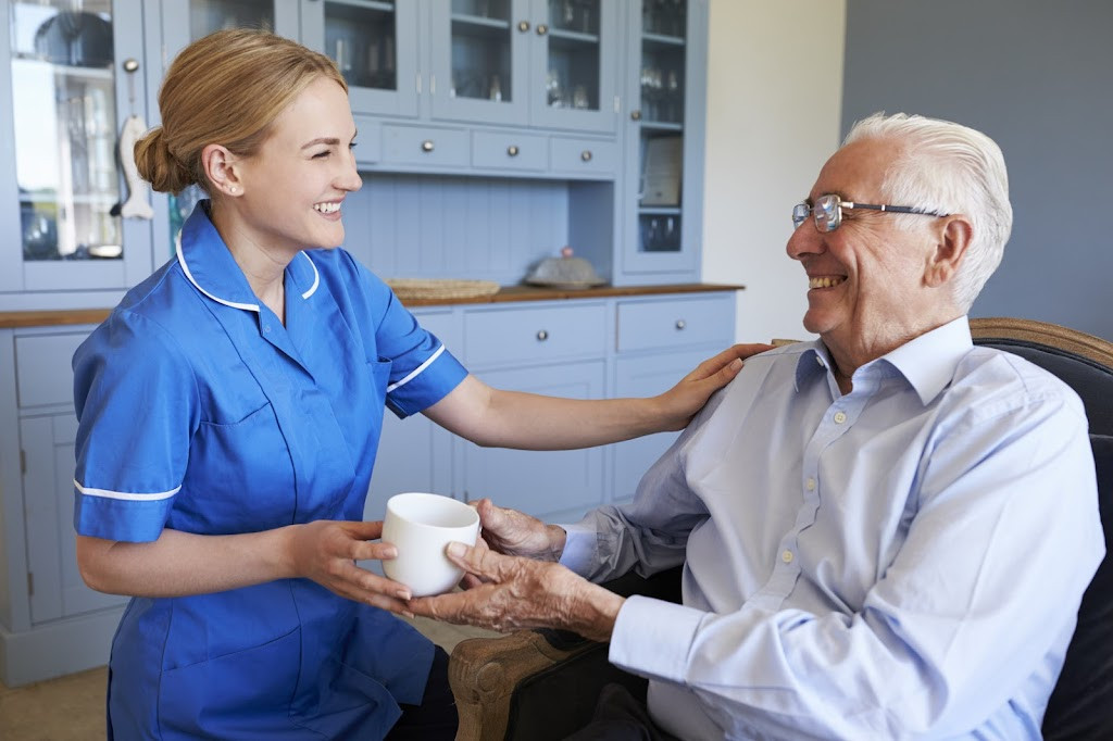 a nurse is giving an elderly a cup of coffee