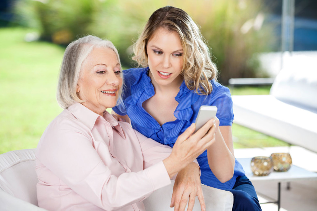 two women sitting on a couch looking at a cell