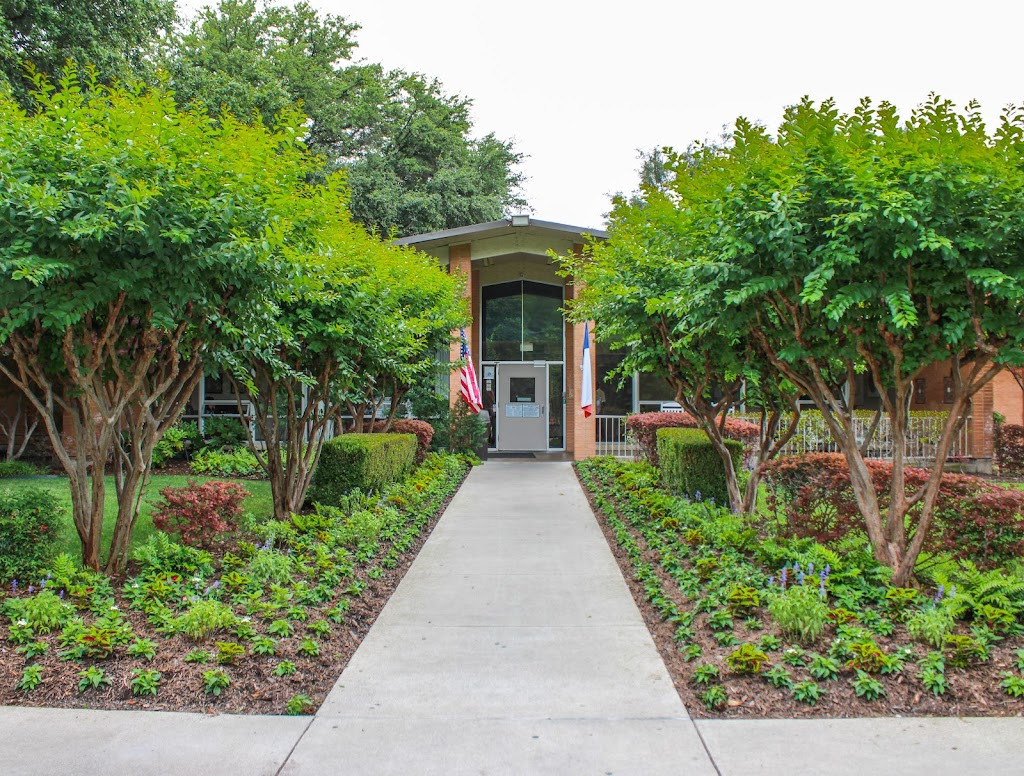 a walkway leading to a house with trees and bushes