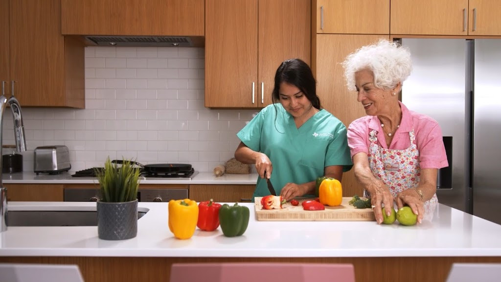 an older woman and young woman preparing food in the kitchen